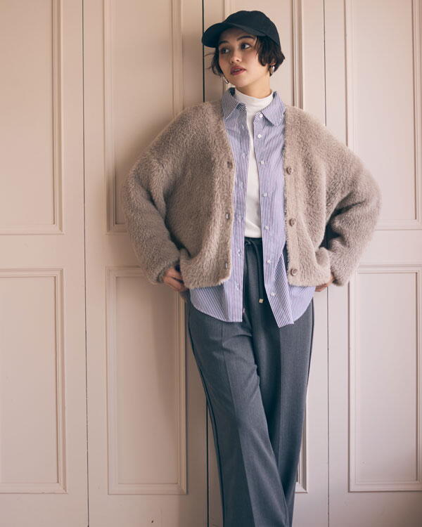 コムサイズム　白いシャツに青いブラウス、ベージュのカーディガンを羽織り、黒いズボンを履いた女性の写真